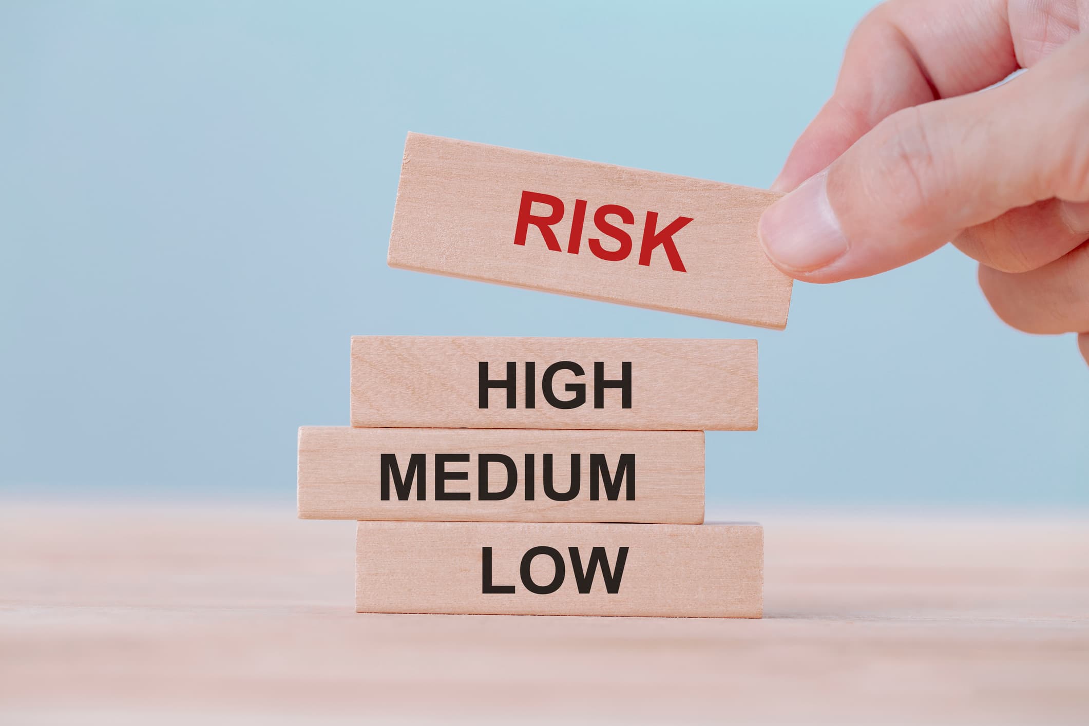 hand holding chooses wooden block cubes with risk word. risk management concept.